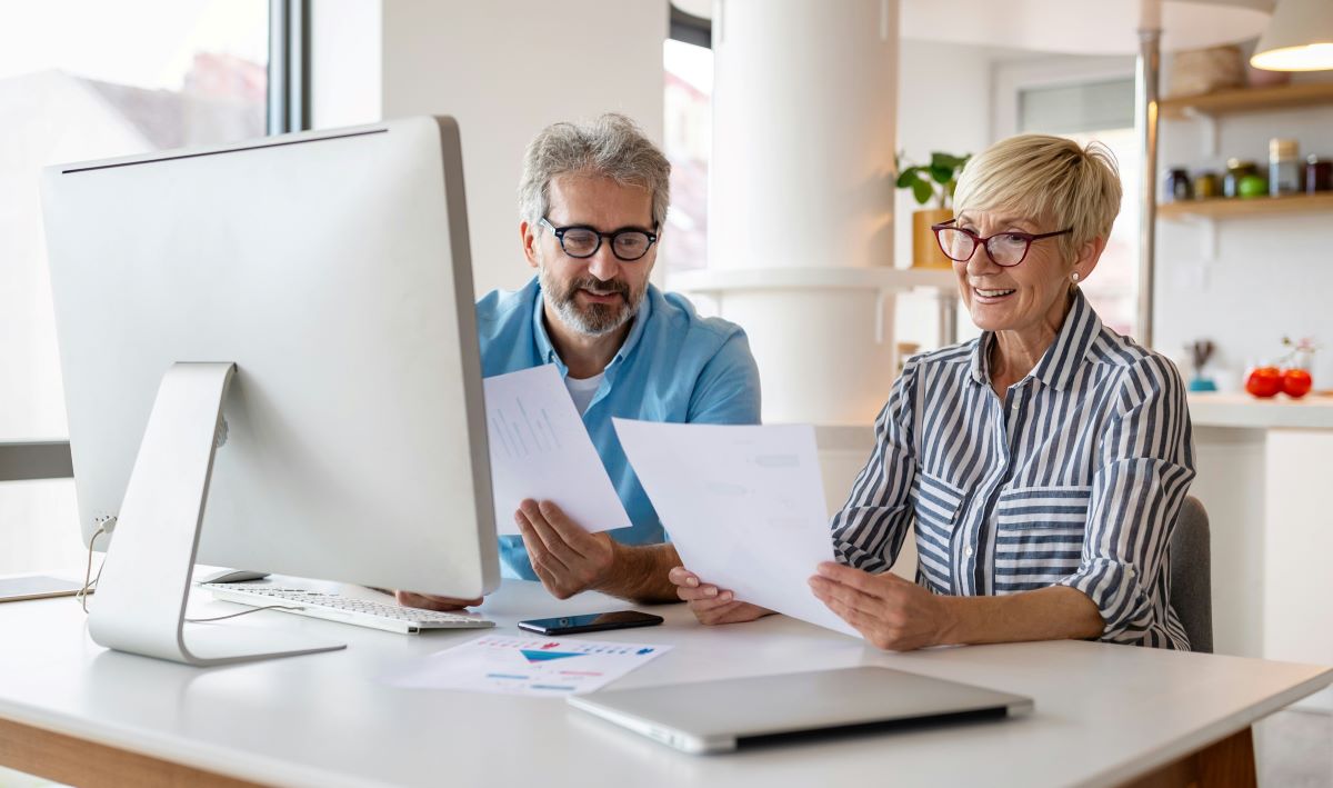 Couple sitting at desk with computer looking at paperwork